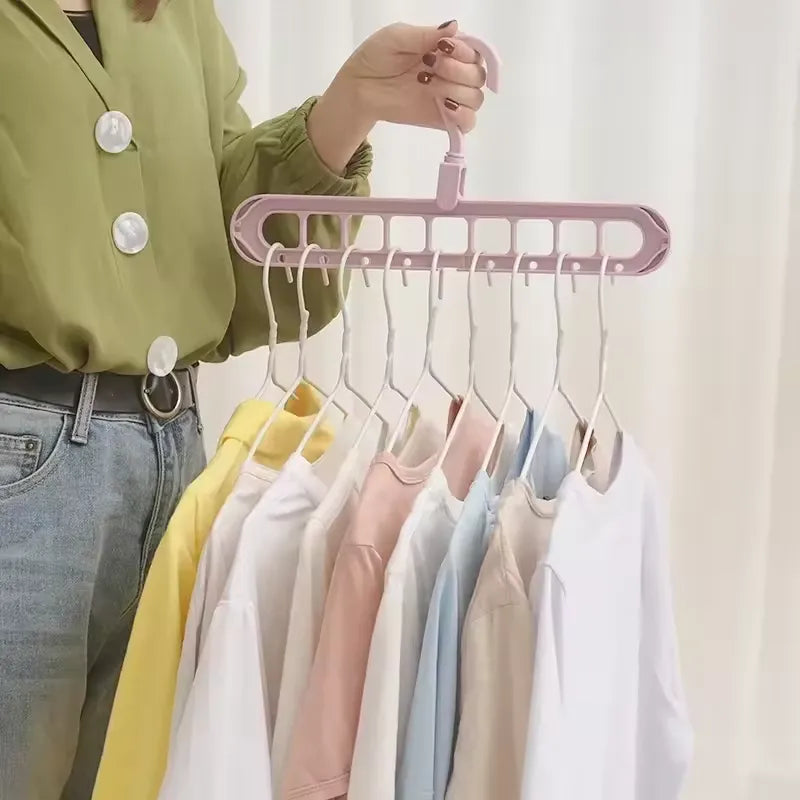 Woman holding a pink Smart Hanger Pro™ horizontally, showcasing 9 colorful t-shirts neatly organized for efficient closet storage.